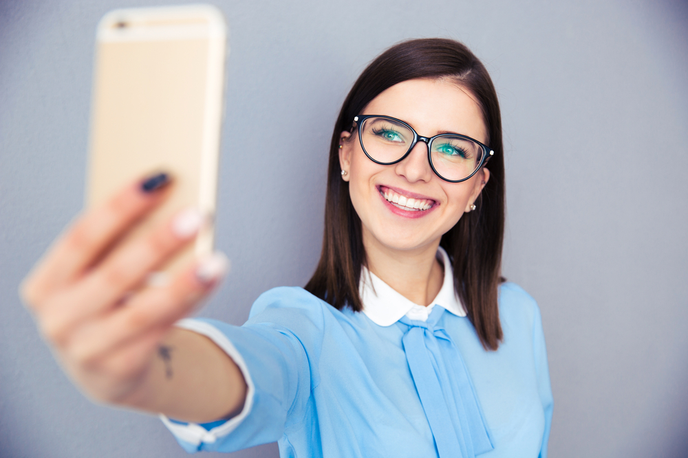 Woman in glasses taking selfie with smartphone