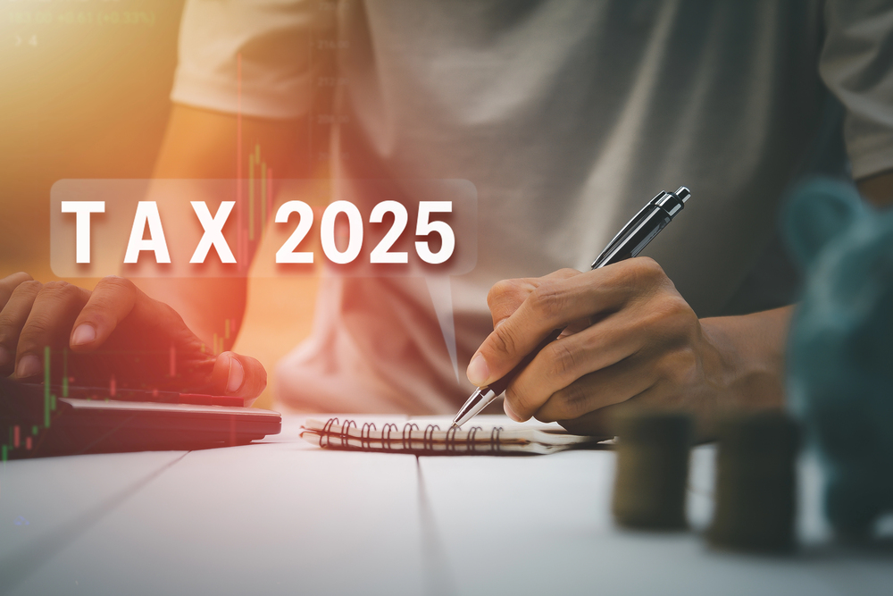 Person writing on notepad with Tax 2025 superimposed over image