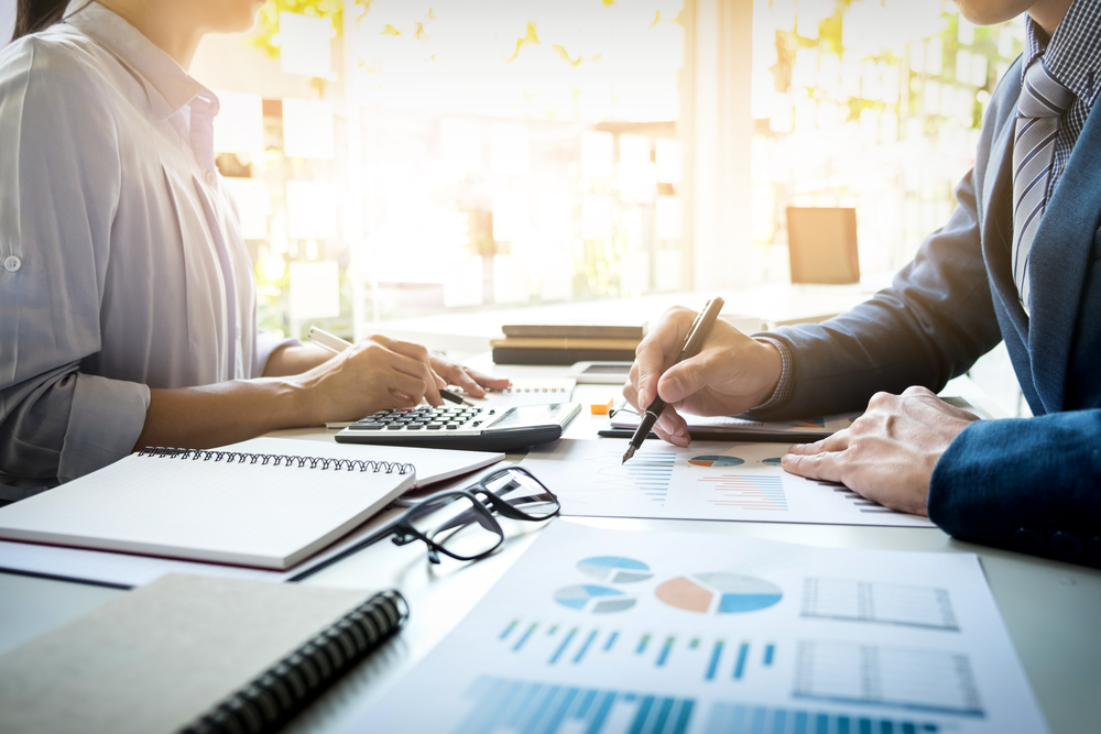 Two men at table looking over spreadsheets