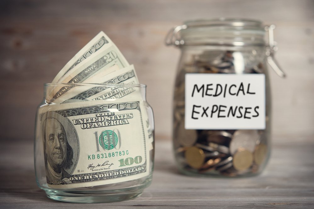 Jar of money labeled medical expenses and glass full of $100 bills