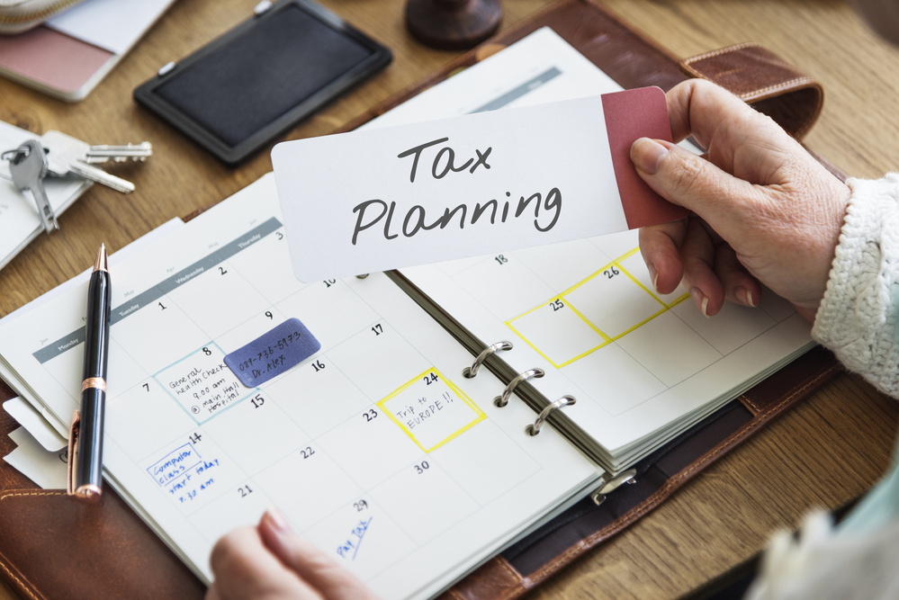 Hand holding "tax planning" note over personal calendar