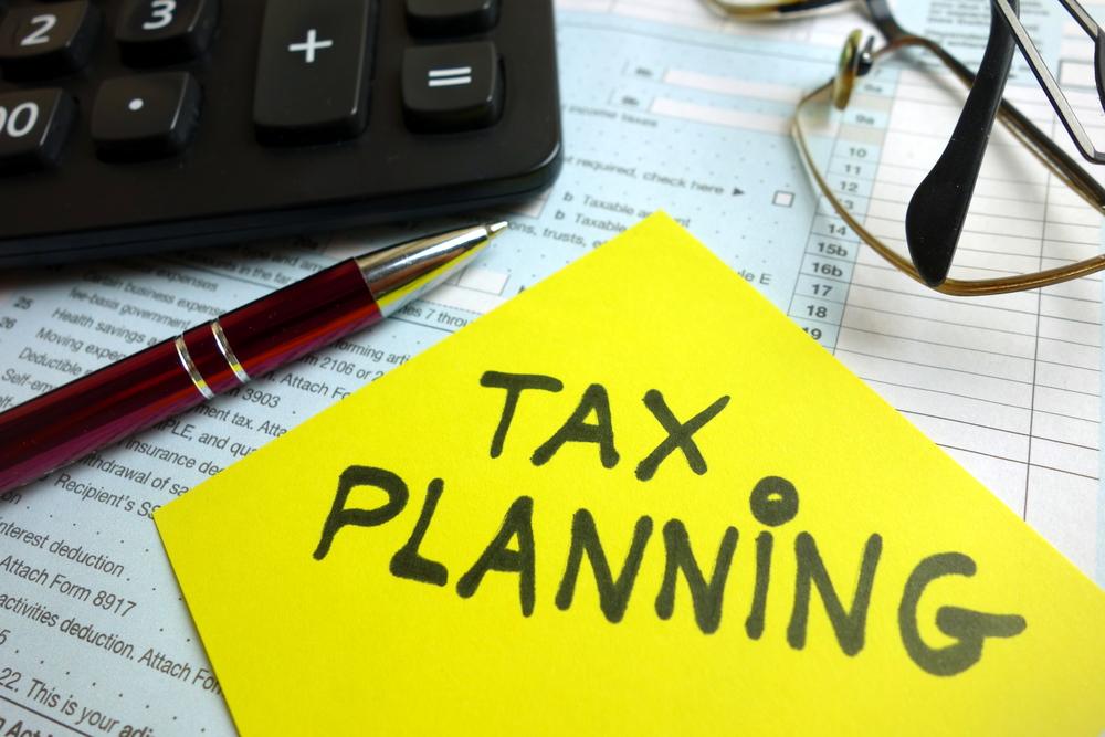 Sticky note that says Tax Planning on desk by laptop