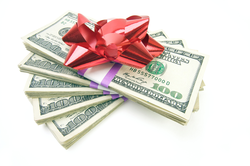 Stack of cash with red bow on white background