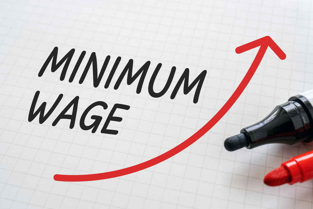 Minimum wage written in black with red arrow pointing up