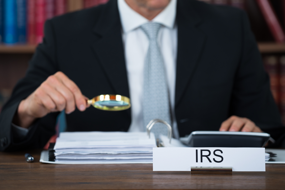 Auditor examining documents with magnifying glass